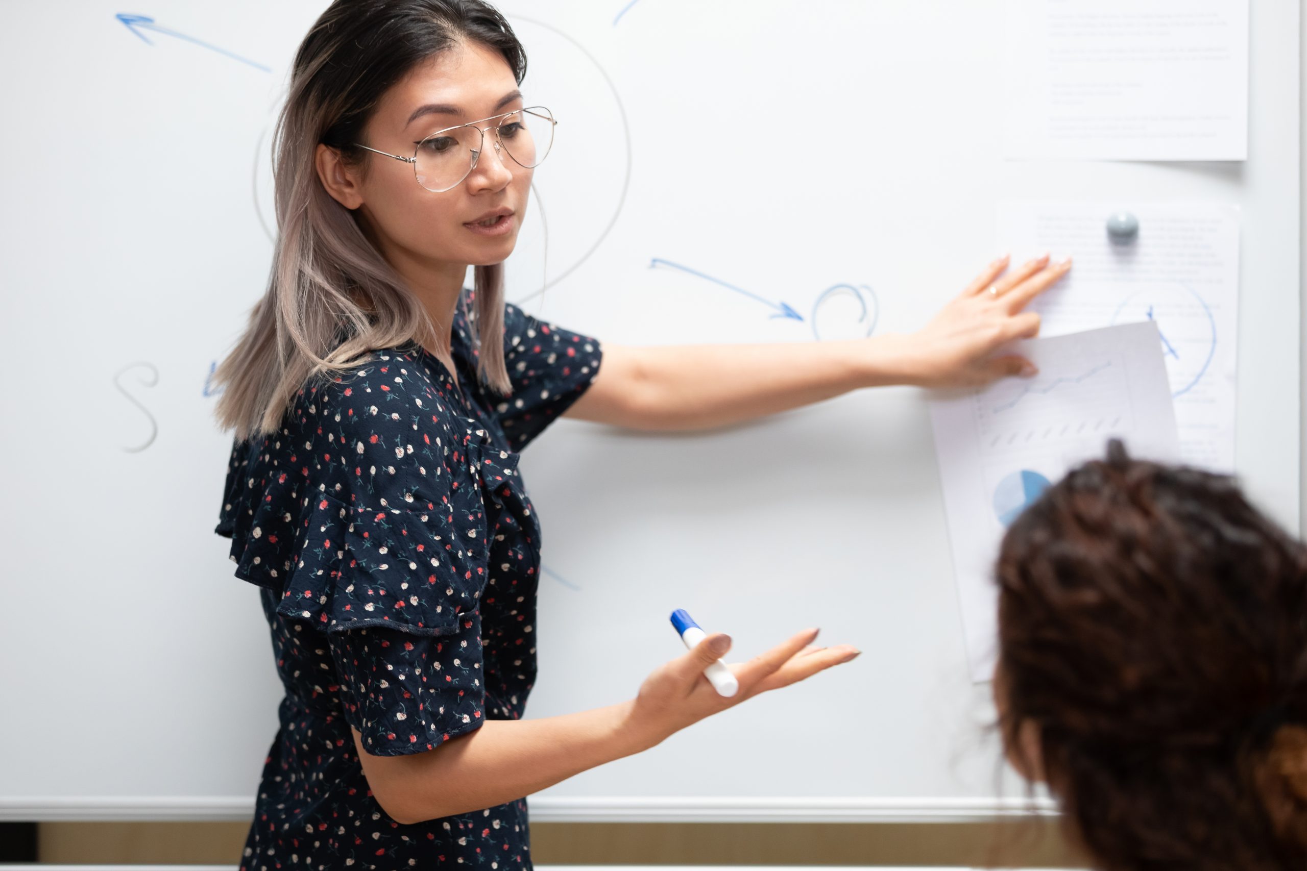 woman teaching other on white board